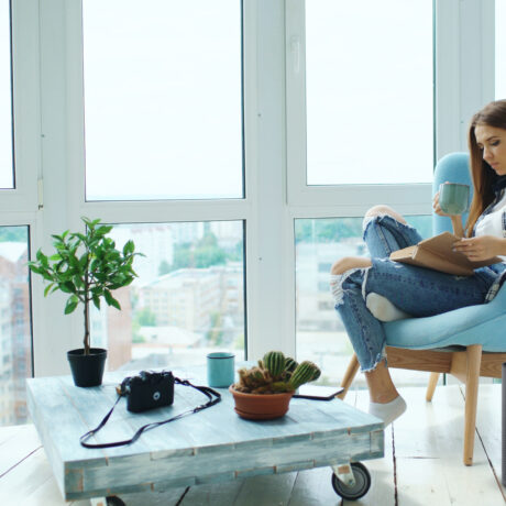 Young attractive woman read book sitting on balcony in modern loft apartment